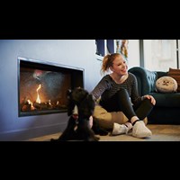 Student pets a dog next to a fireplace