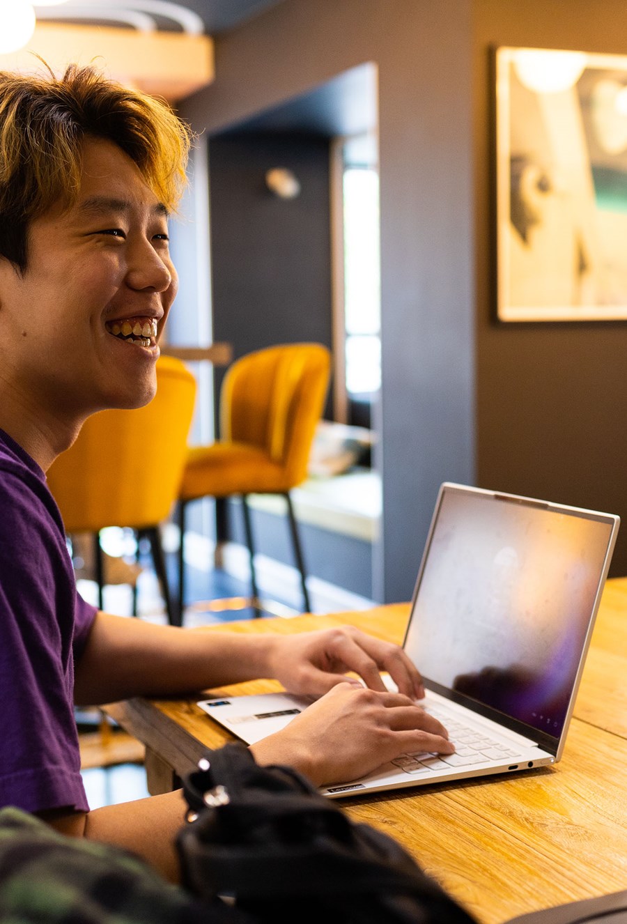 Lifestyle Male Student Laughing While Typing On Laptop