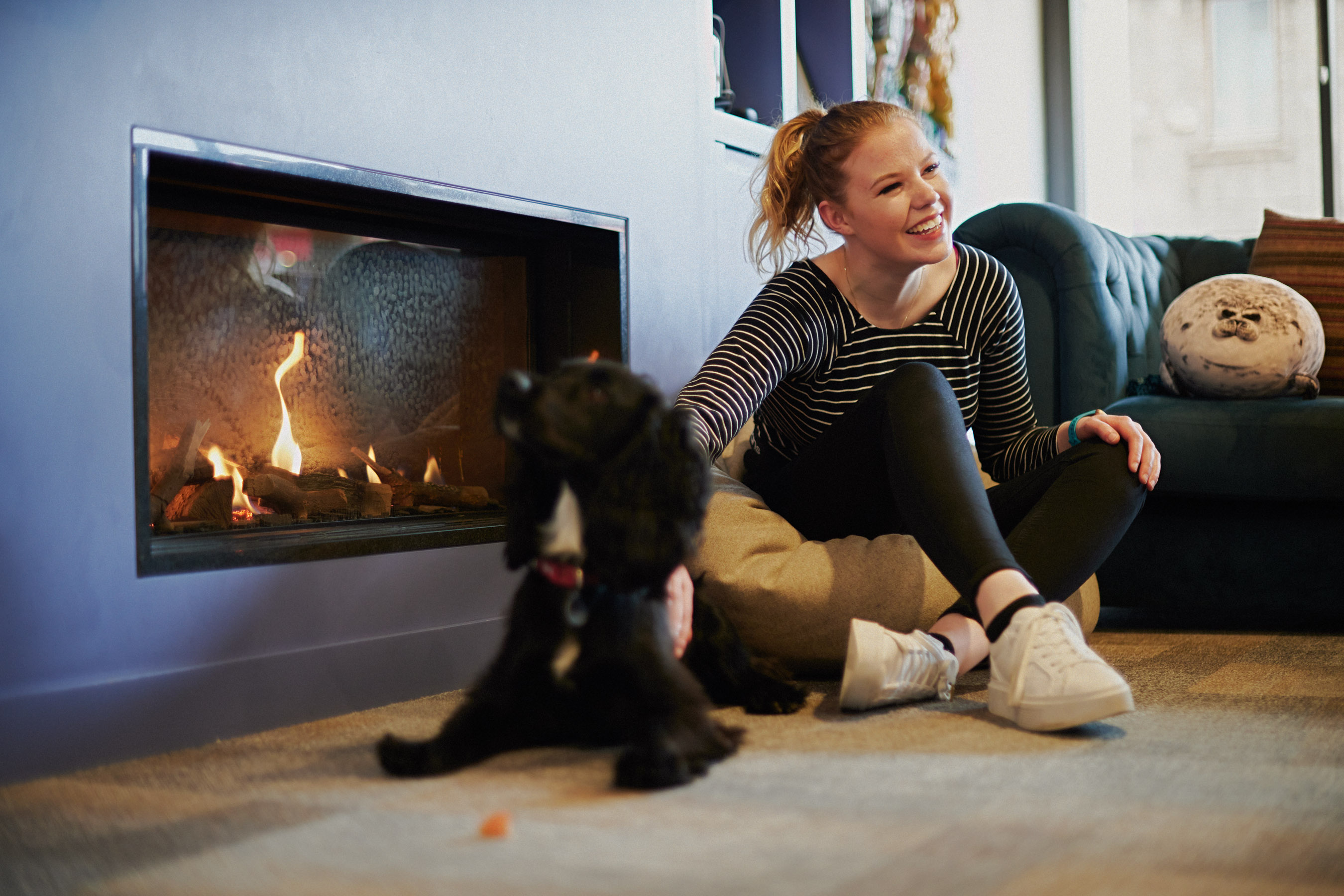 Student pets dog next to a fireplace
