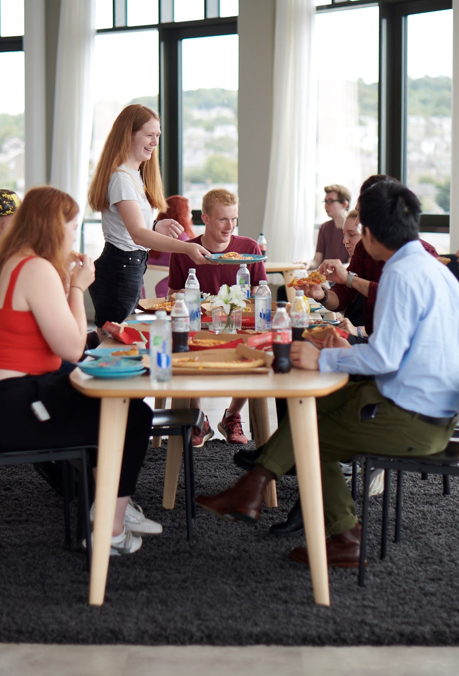 Students sitting at a table in the sky lounge eating food in Lancaster student accommodation