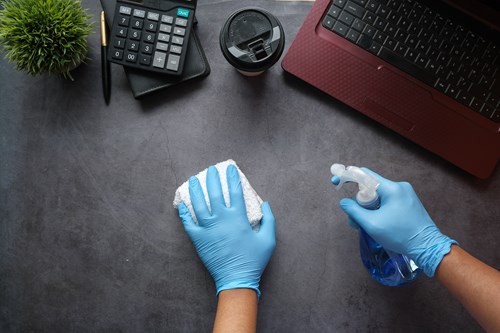 Someone with gloves cleaning a desk